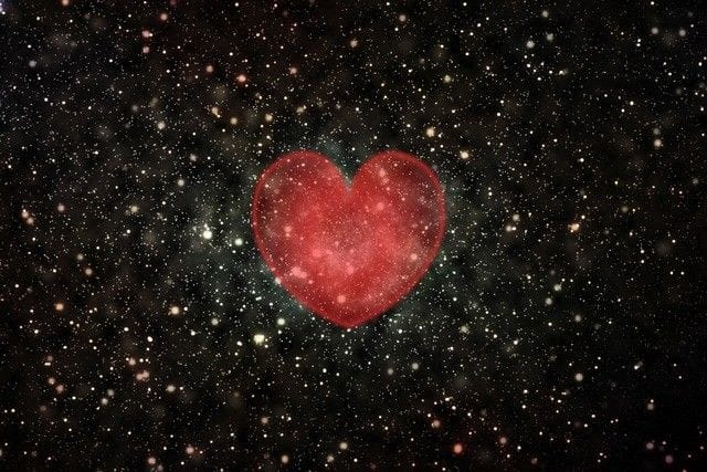 一颗红色的心形图案漂浮在星空背景中，周围散布着星星和光点，呈现出梦幻般的氛围。