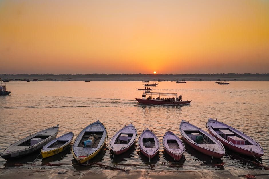 Boats lined up along the Ganges River in Varanasi at sunset, capturing the serene beauty and cultural richness of India.